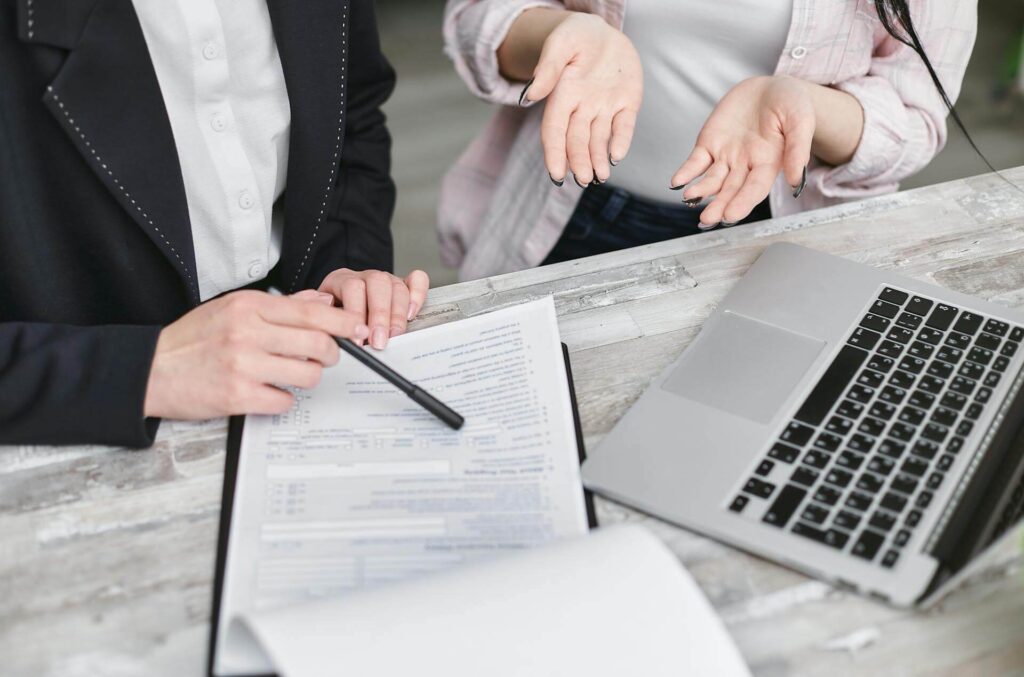 Real estate professionals reviewing loan documents, highlighting the financial challenges of closing costs and the benefits of insured attorney opinion letters for mortgage lenders.